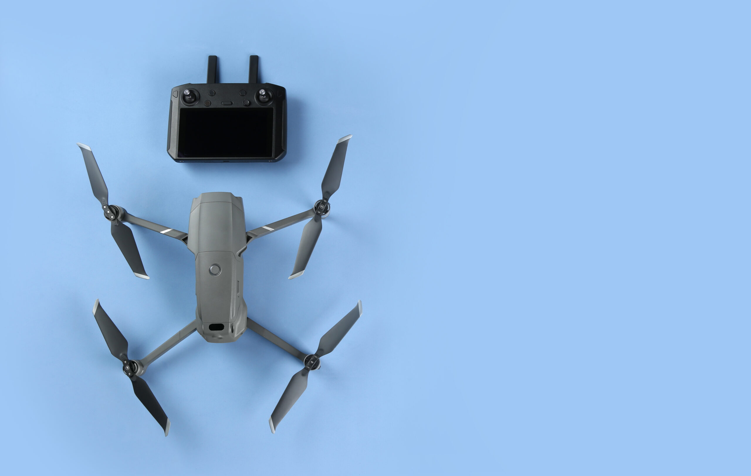 Modern drone with controller on blue background, flat lay. Space